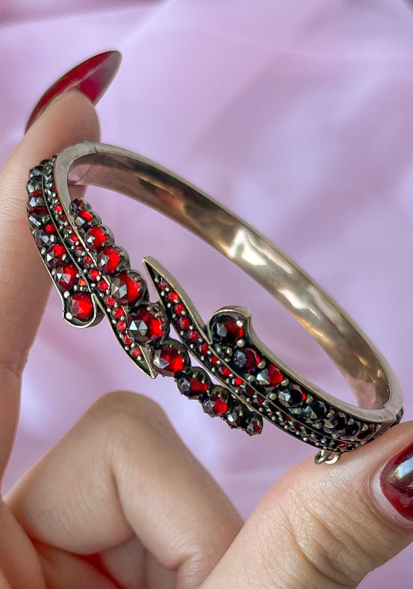Antique garnet swirl bangle bracelet from circa 1890 with ornate gold detailing and deep-red stones