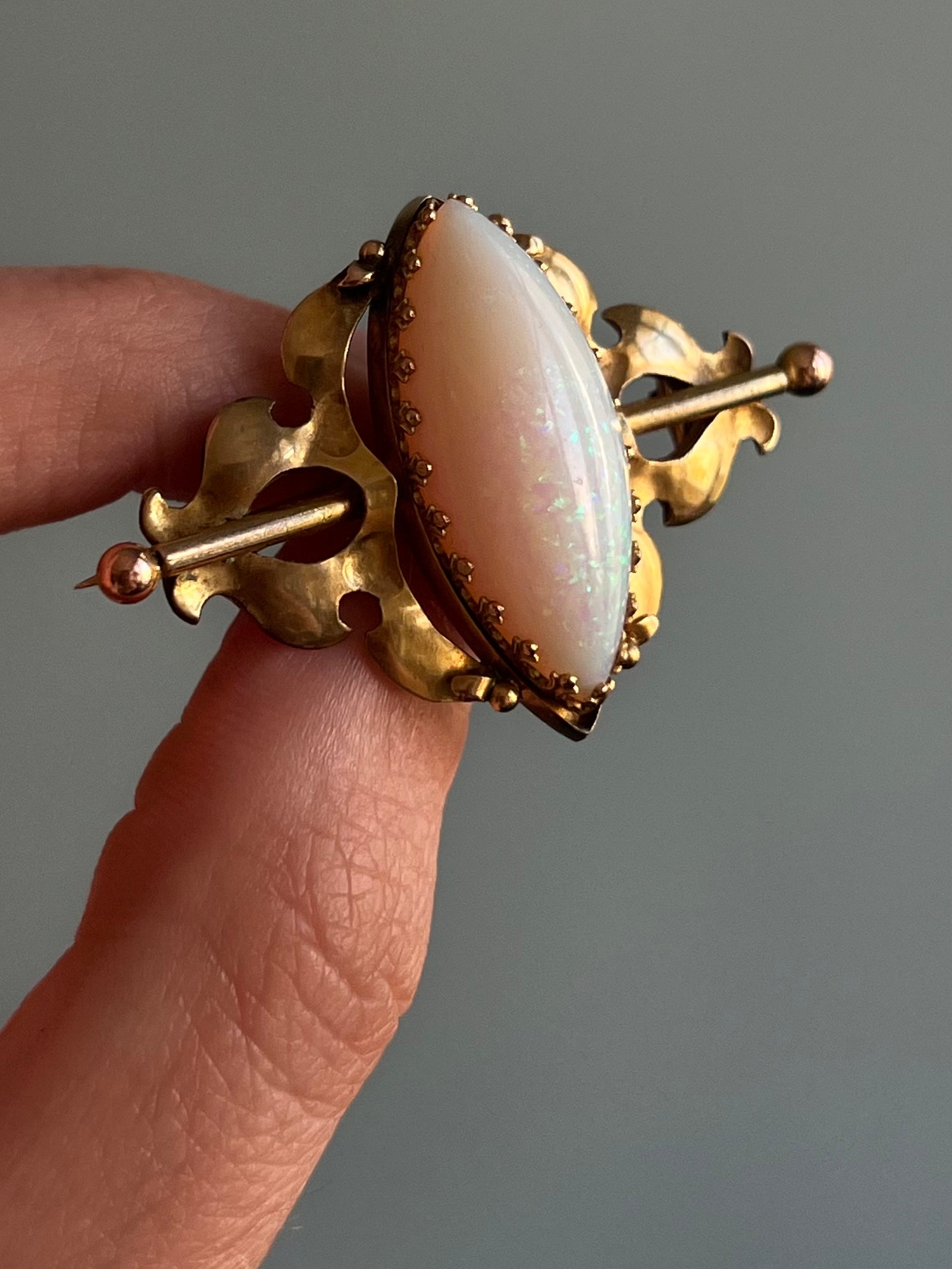 Victorian Opal Brooch with Decorative Bar Setting c. 1890 featuring a vibrant opal gemstone set in an ornate gold bar design, showcasing classic late-19th-century craftsmanship.