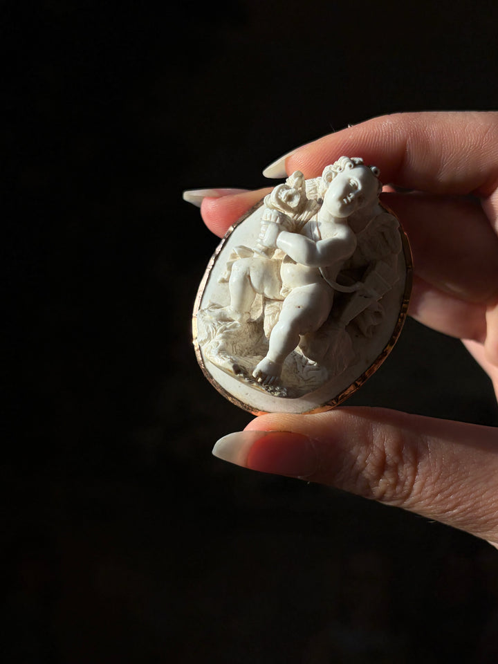Tilted view of the Grand Tour lava Cupid cameo, showing its deep carving and oval gold setting.